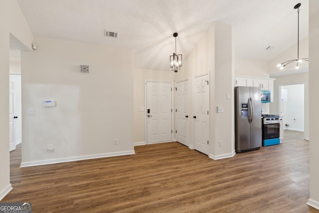 foyer with dark hardwood / wood-style flooring, vaulted ceiling, and an inviting chandelier