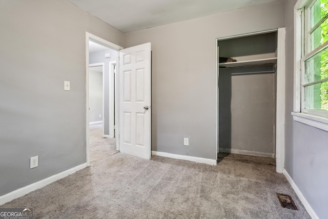 unfurnished bedroom with a closet and light carpet