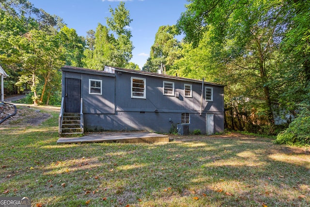 back of property featuring a lawn and central air condition unit