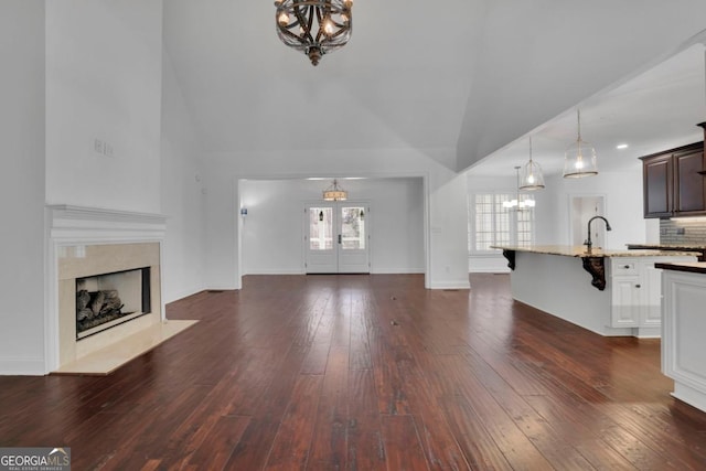 unfurnished living room with french doors, a premium fireplace, dark hardwood / wood-style floors, and a notable chandelier