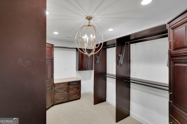 spacious closet featuring an inviting chandelier and light colored carpet