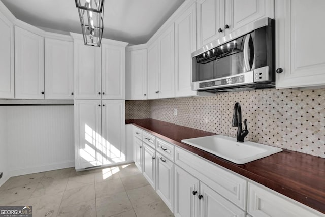 kitchen featuring white cabinetry, sink, decorative backsplash, and hanging light fixtures