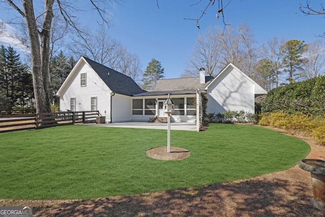 back of house with a sunroom, a patio, and a lawn