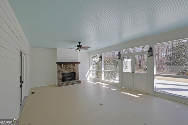 unfurnished living room with ceiling fan and a brick fireplace