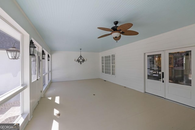 unfurnished sunroom featuring ceiling fan with notable chandelier and french doors