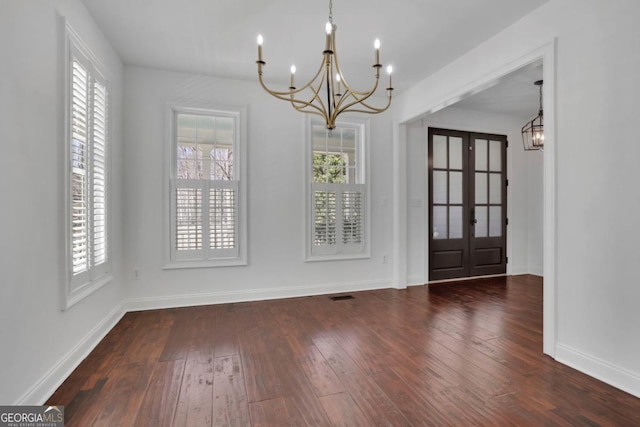 unfurnished dining area featuring dark hardwood / wood-style floors, a wealth of natural light, and a notable chandelier