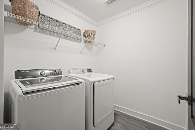 washroom featuring ornamental molding, dark hardwood / wood-style floors, and washing machine and clothes dryer