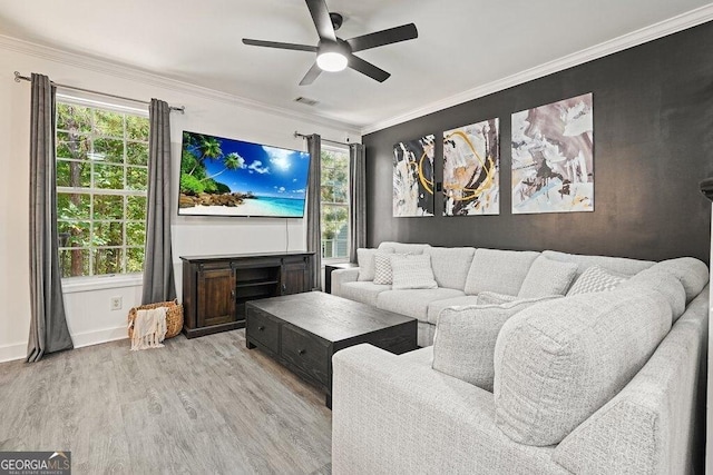 living room featuring crown molding, a healthy amount of sunlight, and light wood-type flooring