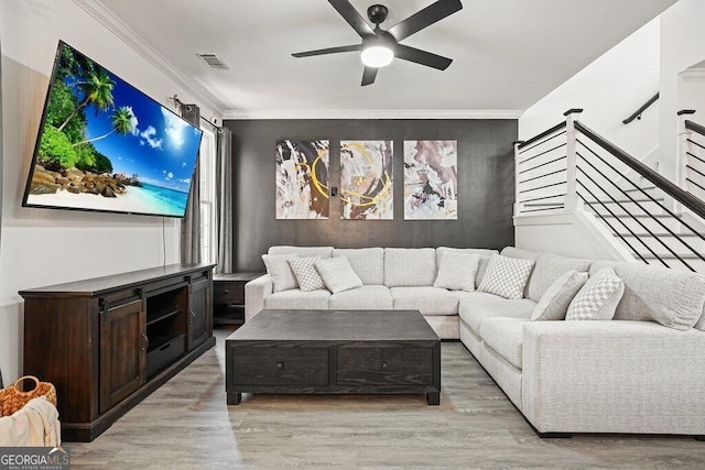 living room featuring crown molding, light hardwood / wood-style flooring, and ceiling fan