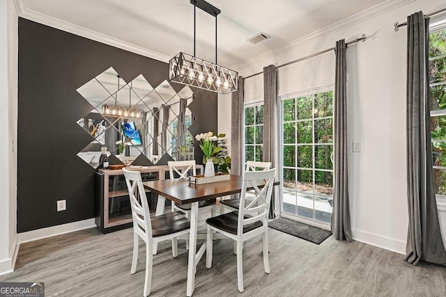 dining space with crown molding, hardwood / wood-style floors, and a notable chandelier