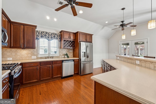 kitchen featuring dark wood-type flooring, sink, vaulted ceiling, hanging light fixtures, and stainless steel appliances