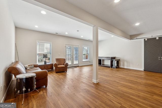 living area featuring wood-type flooring, a barn door, and french doors