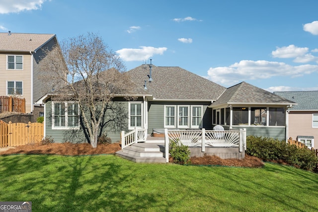 rear view of house featuring a sunroom, a deck, and a lawn