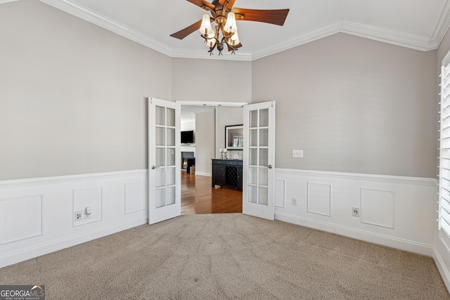 carpeted spare room with crown molding, lofted ceiling, ceiling fan, and french doors