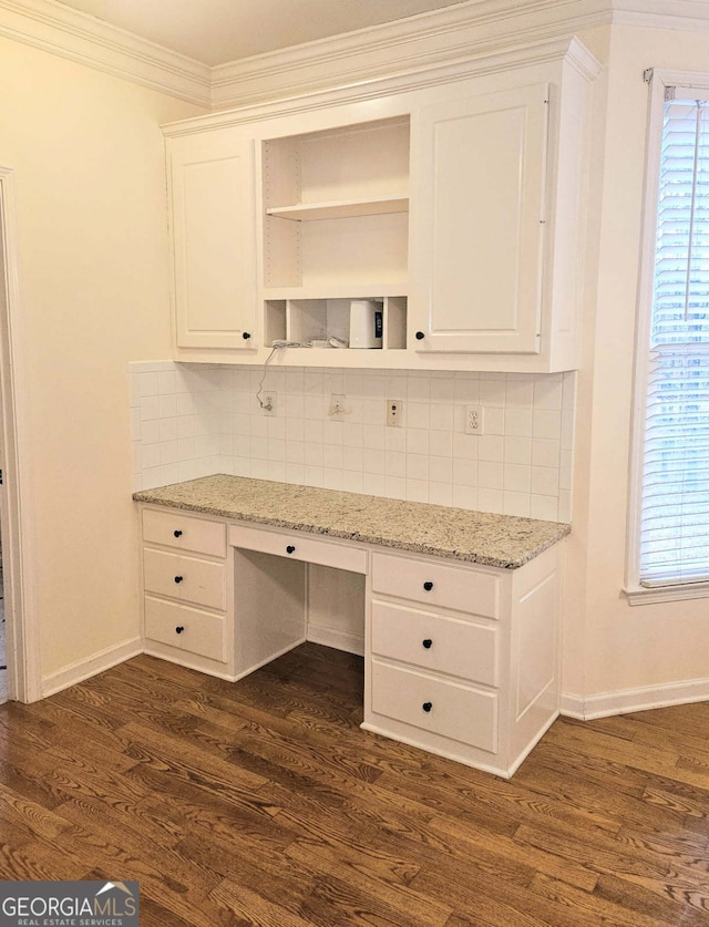 unfurnished office with ornamental molding, dark wood-type flooring, and built in desk