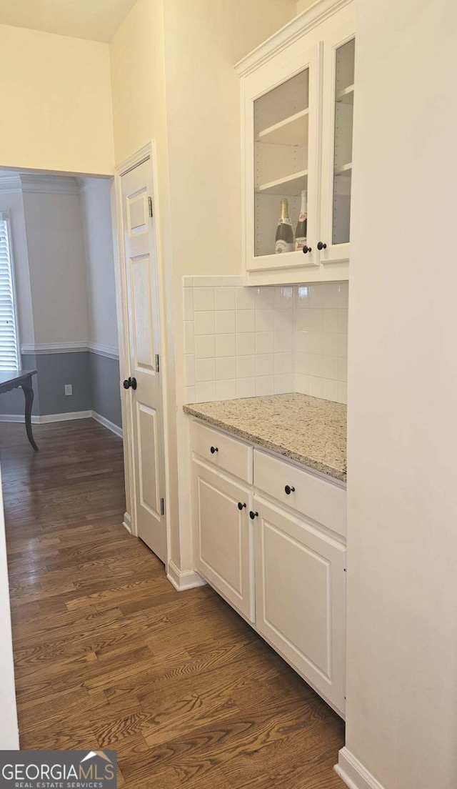 interior space with white cabinetry, backsplash, light stone counters, and dark hardwood / wood-style floors