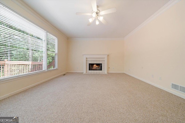 unfurnished living room featuring a tile fireplace, ornamental molding, light carpet, and ceiling fan