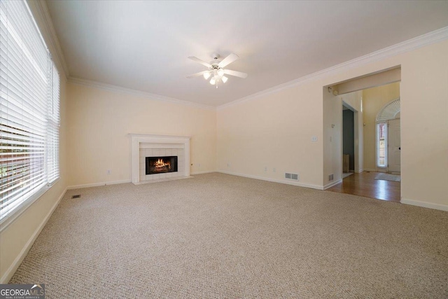 unfurnished living room featuring crown molding, ceiling fan, a fireplace, and carpet floors