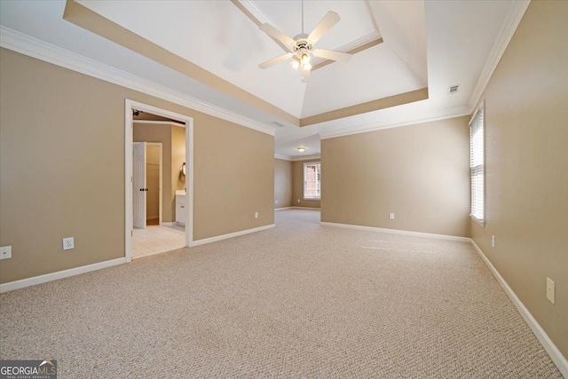 unfurnished room with a raised ceiling, light carpet, crown molding, and baseboards