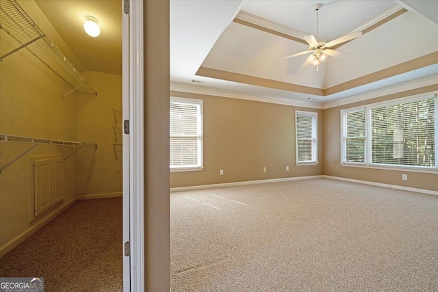 unfurnished room with ceiling fan, a healthy amount of sunlight, a raised ceiling, and light carpet