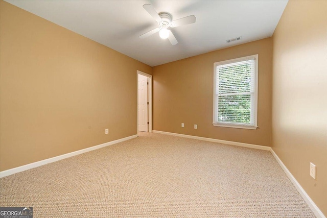 spare room with carpet, visible vents, baseboards, and a ceiling fan