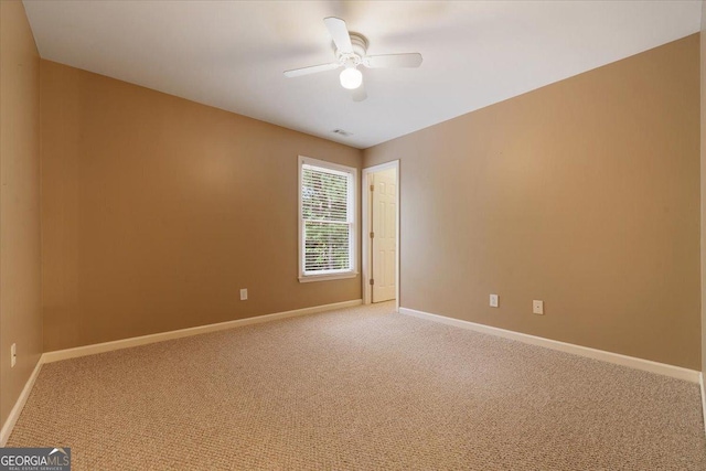 carpeted spare room featuring ceiling fan, visible vents, and baseboards