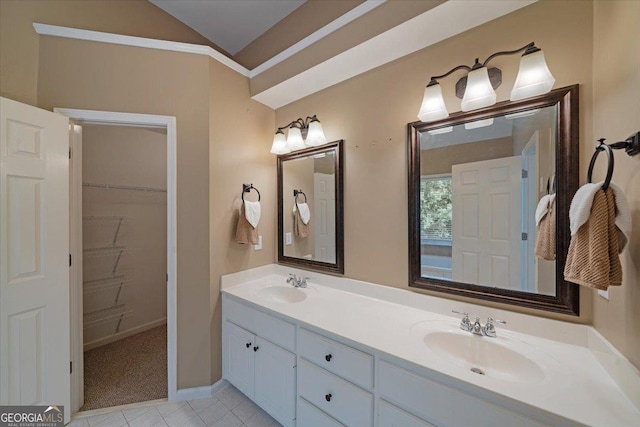 full bath with vaulted ceiling, double vanity, a sink, and a walk in closet