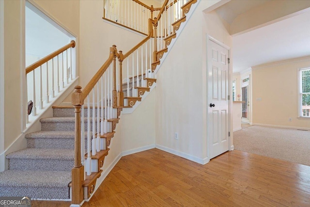 stairs with crown molding and hardwood / wood-style floors