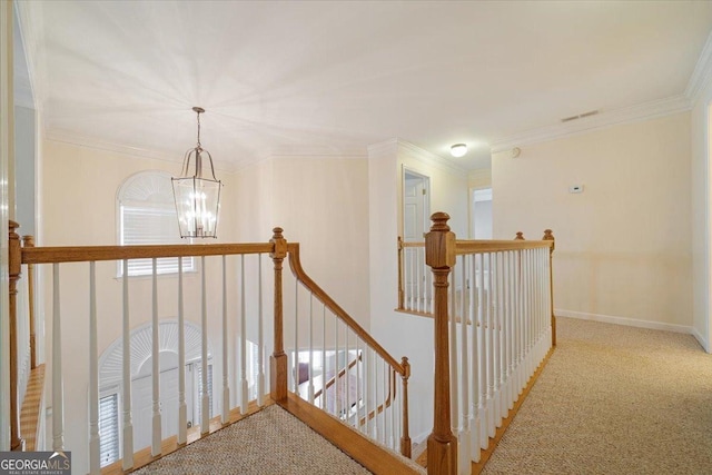 corridor with baseboards, ornamental molding, an upstairs landing, carpet floors, and a notable chandelier