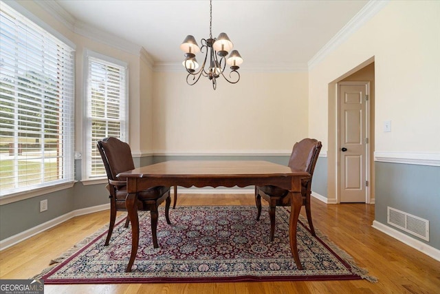 dining area featuring crown molding, a chandelier, and hardwood / wood-style floors