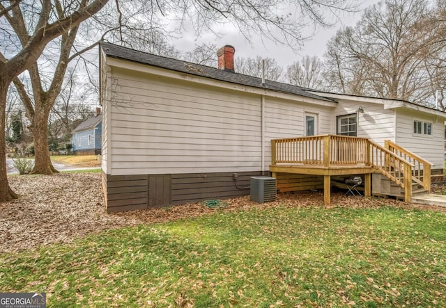 rear view of property with a wooden deck, central AC, and a lawn