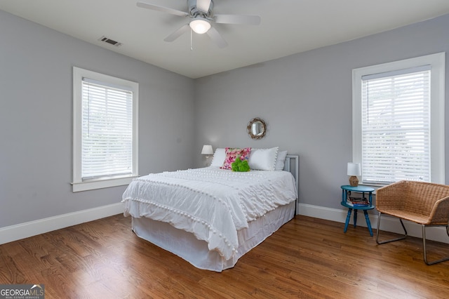 bedroom with hardwood / wood-style flooring, ceiling fan, and multiple windows