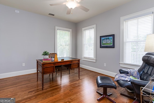 office space featuring wood finished floors, ceiling fan, baseboards, and visible vents