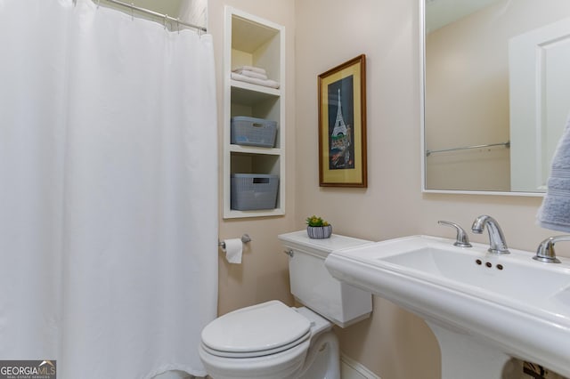 bathroom with toilet, sink, and built in features