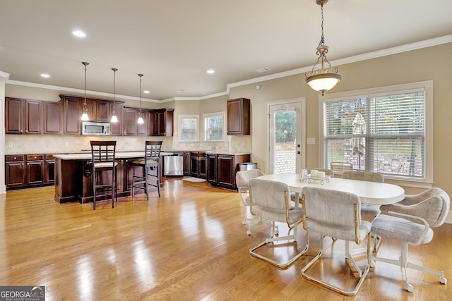 dining space featuring ornamental molding, sink, and light hardwood / wood-style flooring