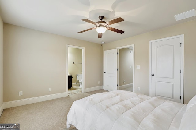 bedroom with ensuite bathroom, light colored carpet, and ceiling fan