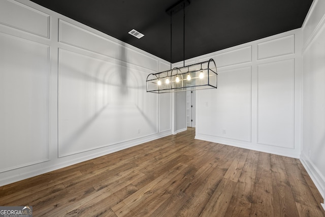 unfurnished dining area featuring hardwood / wood-style flooring and a notable chandelier