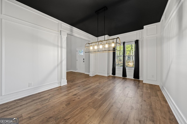 unfurnished dining area featuring a notable chandelier and wood-type flooring