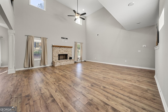 unfurnished living room with ceiling fan, wood-type flooring, and a towering ceiling