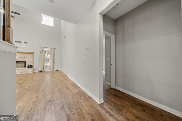 unfurnished living room featuring ceiling fan, hardwood / wood-style floors, and a high ceiling