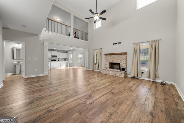 unfurnished living room with ceiling fan, a fireplace, and light hardwood / wood-style flooring