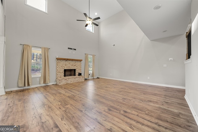 unfurnished living room featuring hardwood / wood-style flooring, ceiling fan, and a towering ceiling