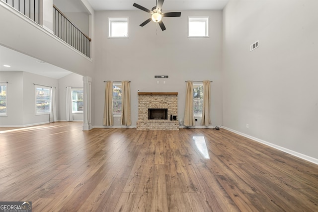 unfurnished living room featuring a healthy amount of sunlight, a brick fireplace, hardwood / wood-style flooring, and ceiling fan