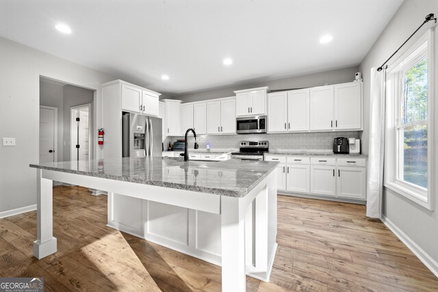 kitchen featuring sink, an island with sink, white cabinets, and appliances with stainless steel finishes