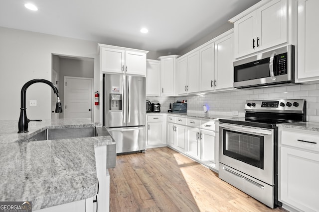 kitchen featuring white cabinetry, light stone counters, and appliances with stainless steel finishes