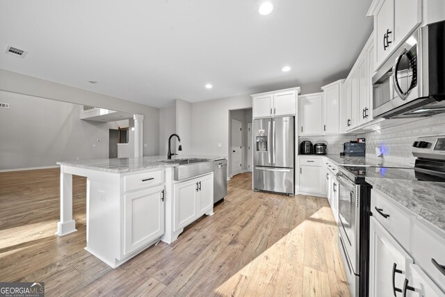 kitchen with white cabinetry, appliances with stainless steel finishes, and a kitchen island with sink