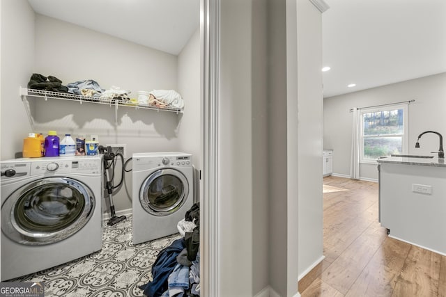 laundry room with sink, washing machine and clothes dryer, and light hardwood / wood-style floors