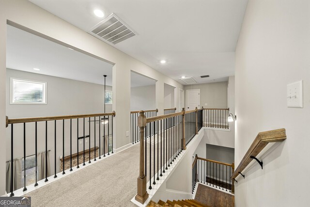 stairway featuring hardwood / wood-style floors, a brick fireplace, and a high ceiling