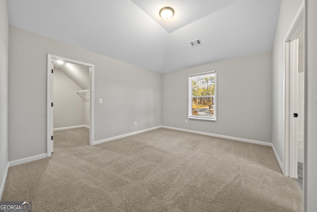 unfurnished bedroom with light colored carpet, lofted ceiling, a closet, and a walk in closet