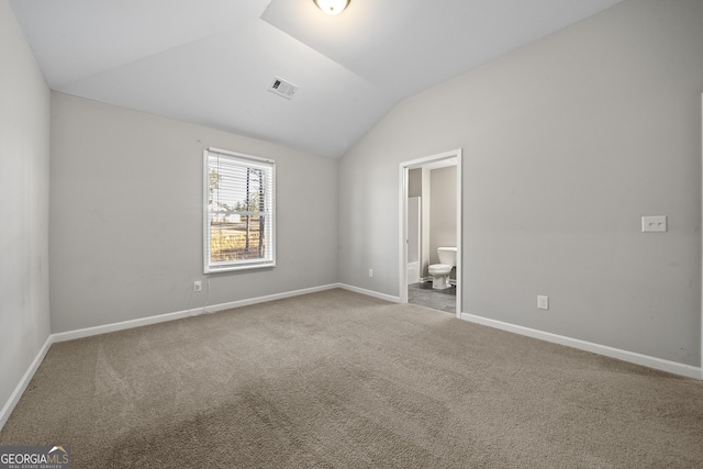 unfurnished bedroom with ensuite bath, vaulted ceiling, and carpet flooring